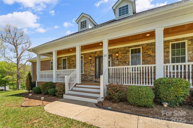 view of exterior entry featuring covered porch and stone siding