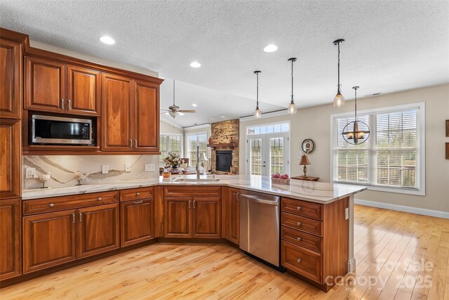 kitchen featuring a peninsula, a sink, light wood finished floors, appliances with stainless steel finishes, and a wealth of natural light