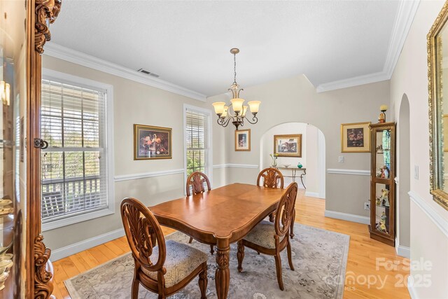 dining room with visible vents, arched walkways, light wood finished floors, and an inviting chandelier