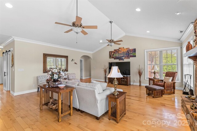 living room with vaulted ceiling, arched walkways, baseboards, and a ceiling fan