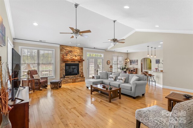living room with ceiling fan, lofted ceiling, light wood finished floors, and a fireplace