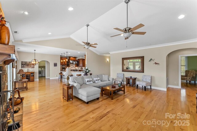 living room featuring arched walkways, ceiling fan, and light wood-style floors