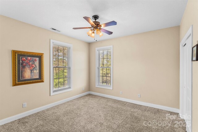 carpeted empty room featuring baseboards, ceiling fan, and visible vents
