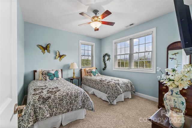 carpeted bedroom featuring baseboards, ceiling fan, and visible vents