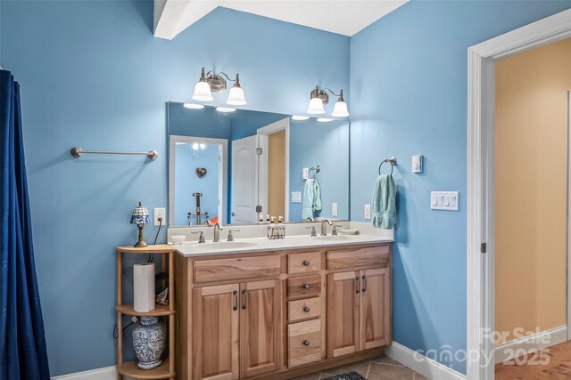 bathroom with a sink, baseboards, and double vanity