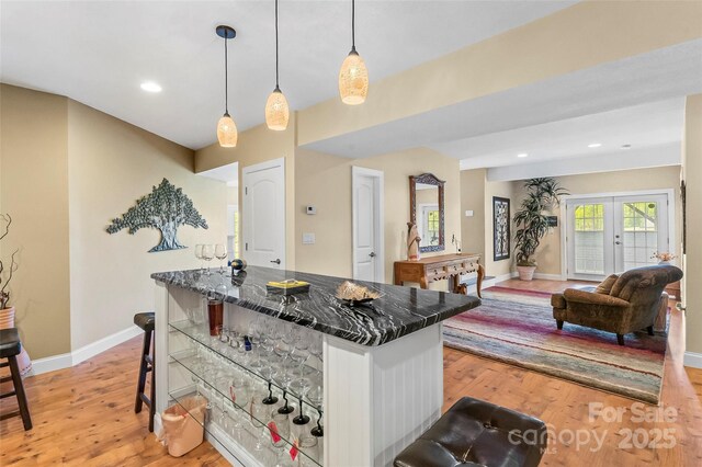 kitchen with a kitchen island, baseboards, a breakfast bar, and light wood-style flooring