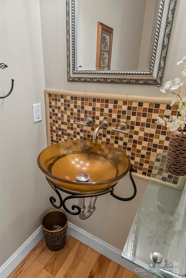 interior details with a sink, baseboards, backsplash, and wood finished floors