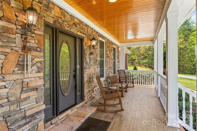 doorway to property featuring covered porch and stone siding