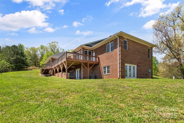 back of house featuring central air condition unit, a lawn, french doors, and a wooden deck