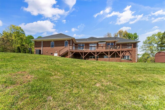 back of property with a lawn, a wooden deck, and brick siding