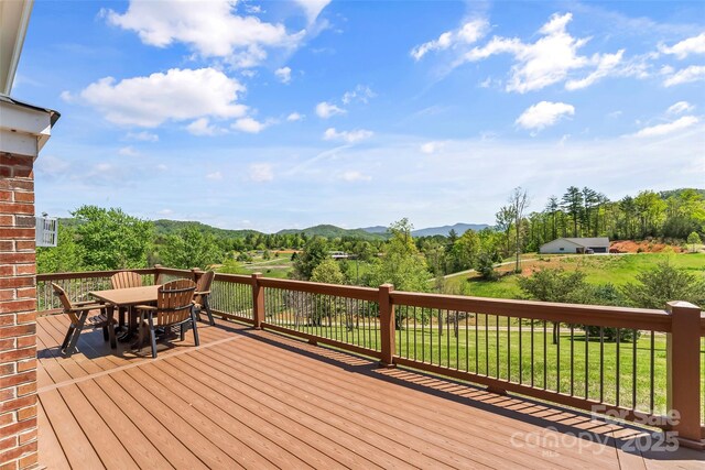 wooden terrace with a yard, a mountain view, and outdoor dining space