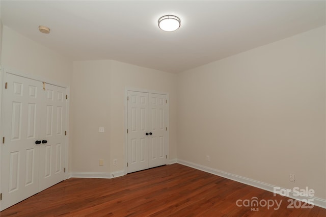4410 Laurel Twig Ct, Charlotte, NC 28215 - unfurnished bedroom featuring two closets, wood finished floors, and baseboards