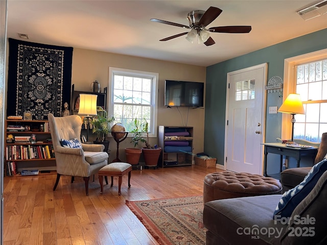 living room featuring a healthy amount of sunlight, ceiling fan, hardwood / wood-style flooring, and visible vents