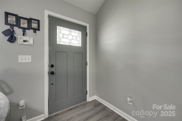 foyer featuring baseboards and wood finished floors