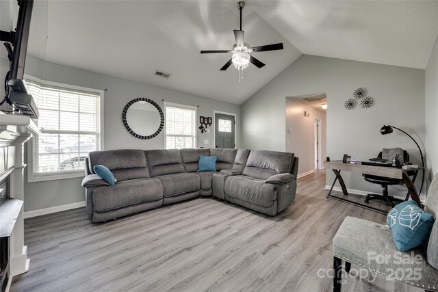 living room featuring a wealth of natural light, wood finished floors, visible vents, and vaulted ceiling
