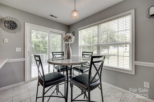 dining area featuring marble finish floor, baseboards, and a healthy amount of sunlight