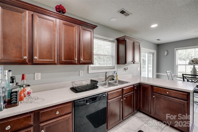 kitchen featuring a sink, a peninsula, visible vents, dishwasher, and light countertops