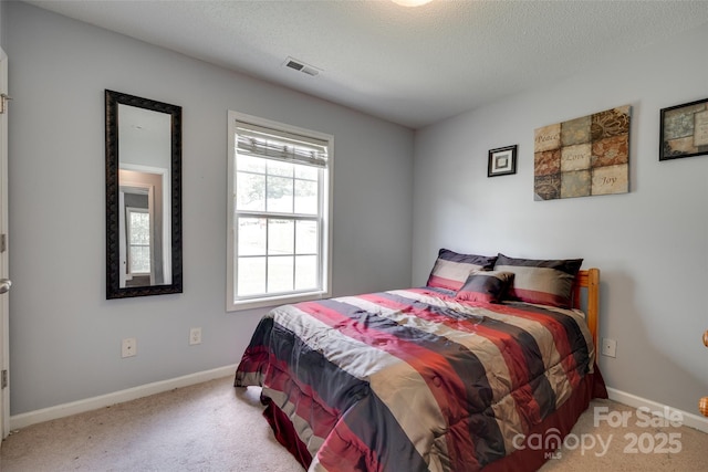 carpeted bedroom featuring baseboards, visible vents, and a textured ceiling