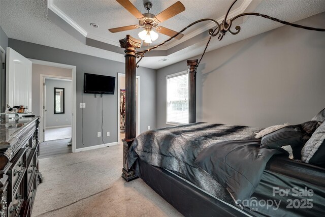 bedroom with a tray ceiling, a textured ceiling, light carpet, and ornamental molding