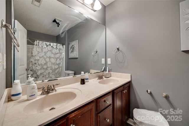 bathroom with double vanity, toilet, visible vents, and a sink