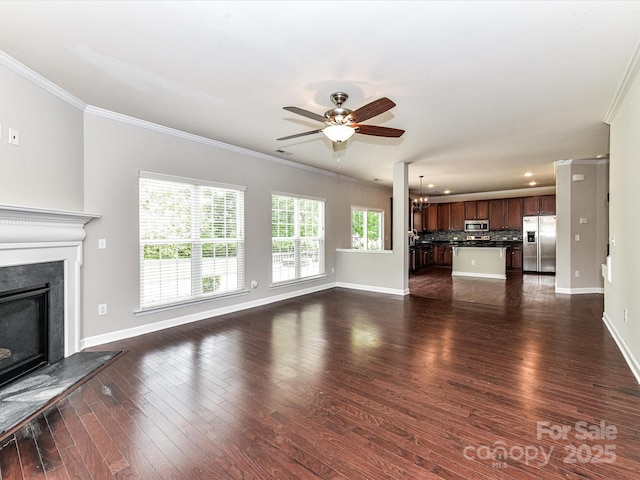 2369 Baxter Pl SE, Concord, NC 28025 - unfurnished living room with crown molding, dark wood-style flooring, baseboards, and ceiling fan with notable chandelier