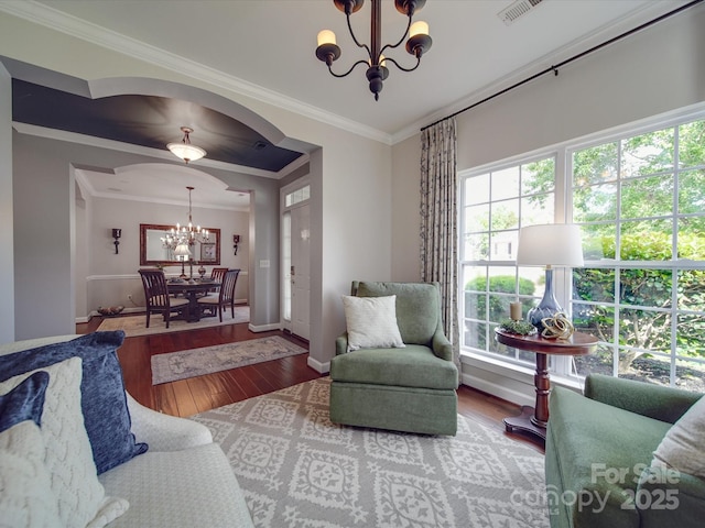 living area with an inviting chandelier, plenty of natural light, visible vents, and hardwood / wood-style flooring