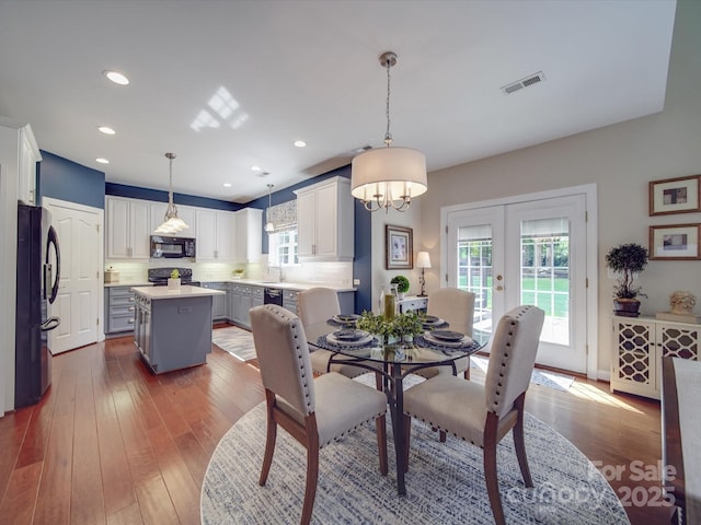 dining area featuring a notable chandelier, wood-type flooring, french doors, recessed lighting, and visible vents