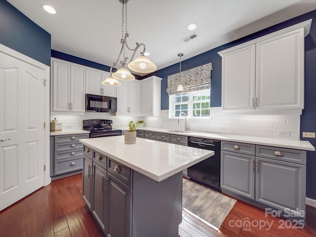 kitchen with a sink, white cabinets, black appliances, and gray cabinetry