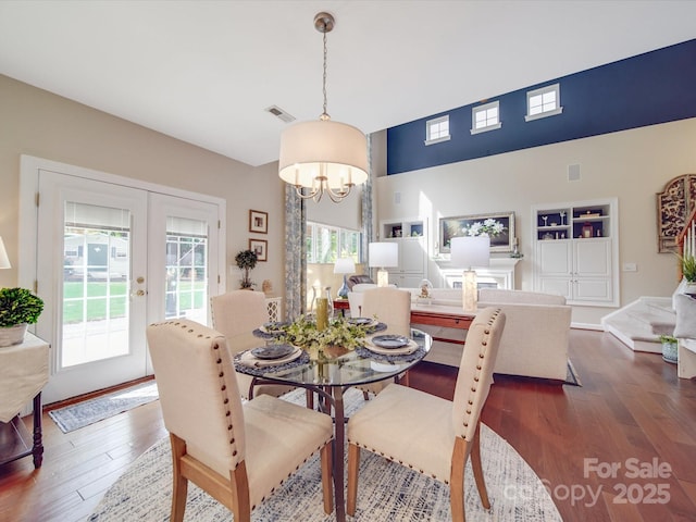 dining space with a wealth of natural light, a notable chandelier, dark wood-type flooring, and visible vents