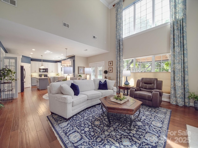 living area with a wealth of natural light, dark wood-style flooring, and visible vents