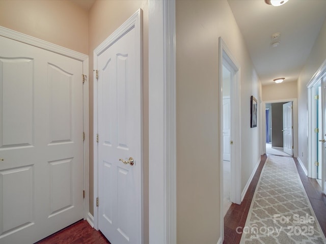 hallway featuring baseboards and dark wood finished floors