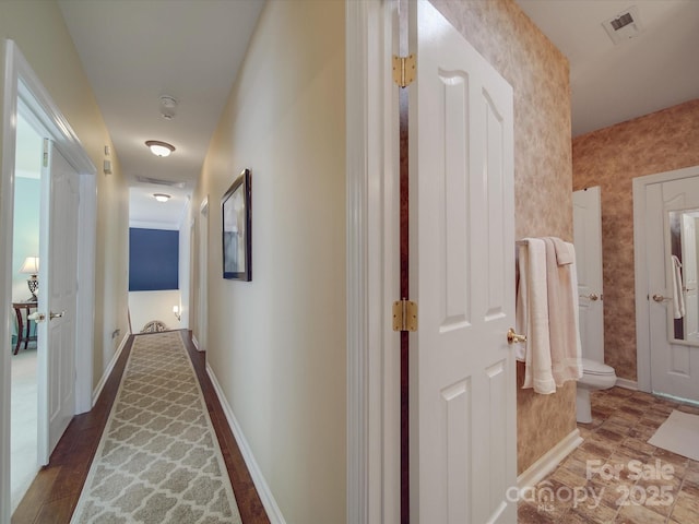 hall featuring baseboards and visible vents