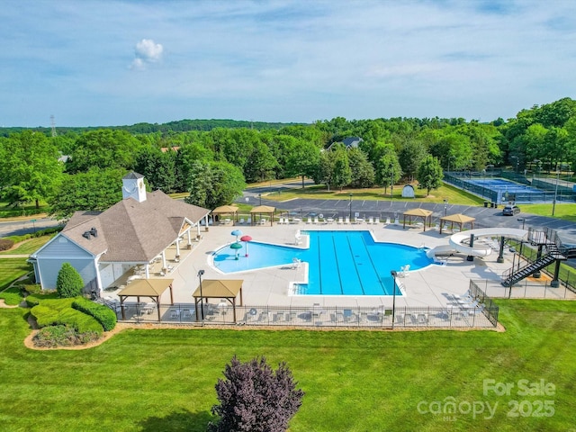 community pool with fence, a yard, and a water slide