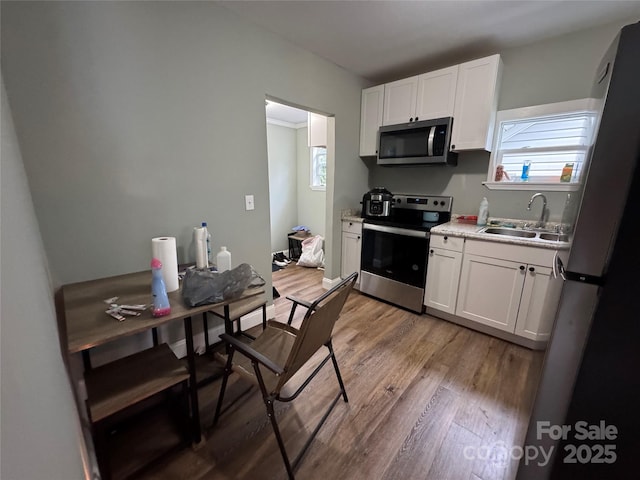 81 Academy Ave NW, Concord, NC 28025 - kitchen featuring appliances with stainless steel finishes, a sink, light wood finished floors, and white cabinetry