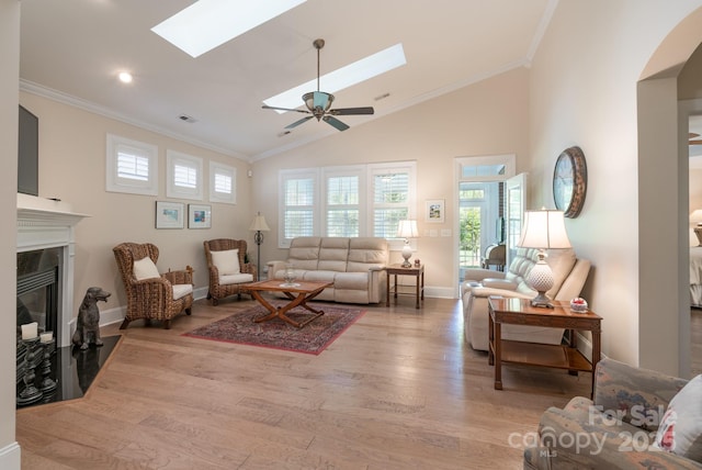 11008 Round Rock Rd, Charlotte, NC 28277 - living room featuring a skylight, crown molding, a fireplace with flush hearth, light wood-type flooring, and high vaulted ceiling