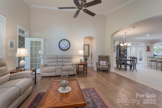 11008 Round Rock Rd, Charlotte, NC 28277 - living room featuring arched walkways, ornamental molding, ceiling fan with notable chandelier, and a high ceiling