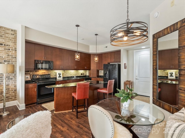 kitchen with a breakfast bar, black appliances, backsplash, a kitchen island, and dark countertops