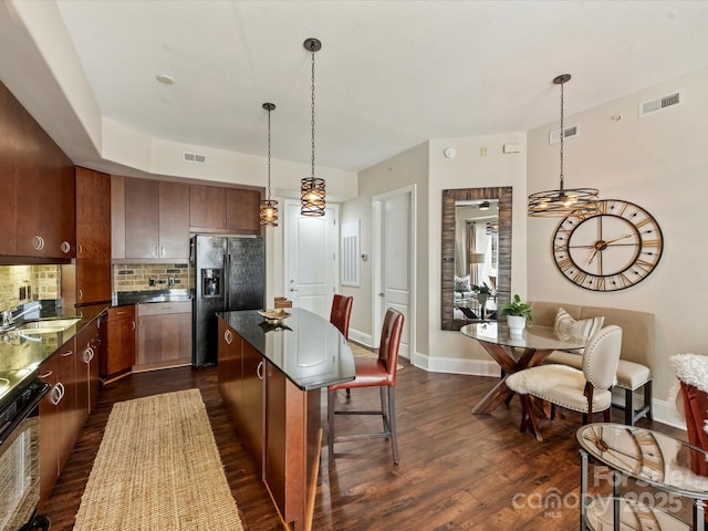 kitchen with black fridge with ice dispenser, a sink, dark wood finished floors, dark countertops, and backsplash