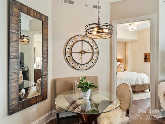 dining area featuring an inviting chandelier, visible vents, wood finished floors, and baseboards