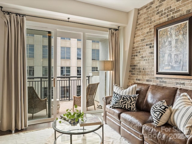 living room with wood finished floors and brick wall