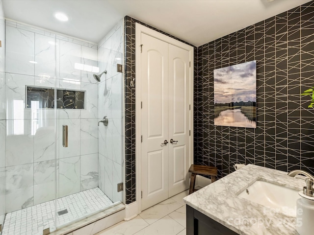 full bath featuring tile walls, marble finish floors, a marble finish shower, vanity, and recessed lighting