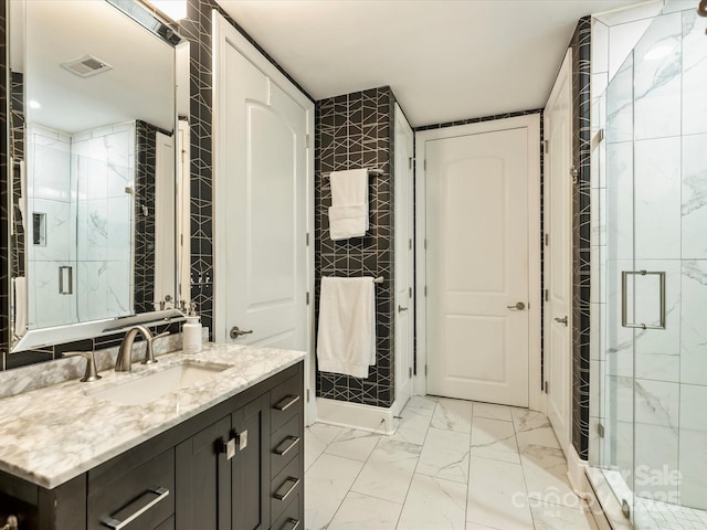 bathroom with a shower stall, marble look tiles, and vanity