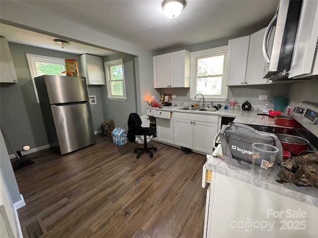 1010 Tennessee St, Kannapolis, NC 28083 - kitchen featuring appliances with stainless steel finishes, a sink, dark wood-type flooring, light countertops, and white cabinetry