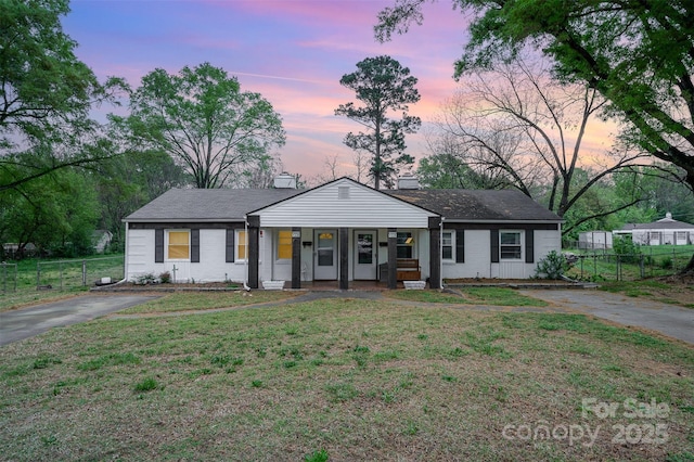 view of front of house featuring driveway, fence, a porch, and a front lawn