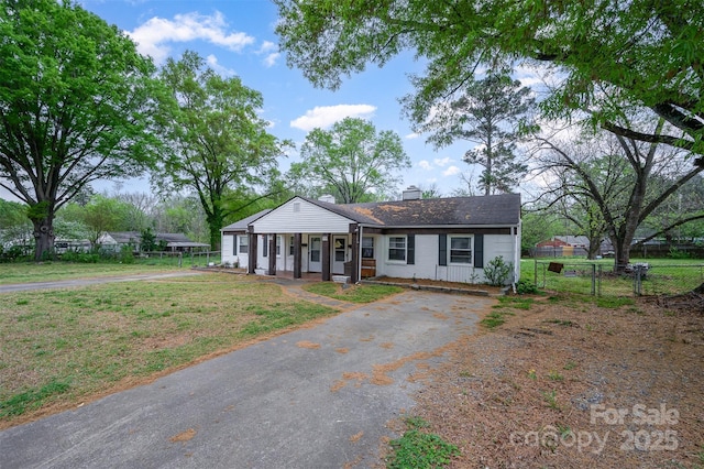 view of front of home featuring a porch, a front yard, a chimney, aphalt driveway, and fence
