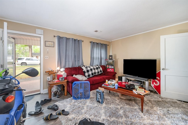 living area with baseboards, visible vents, wood finished floors, and crown molding