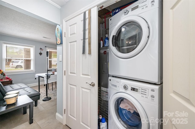 laundry room with laundry area, light tile patterned floors, baseboards, stacked washer and clothes dryer, and a textured ceiling