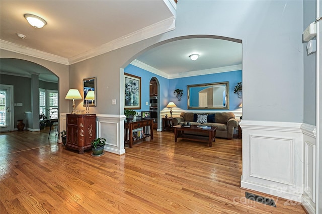 11232 Tradition View Dr, Charlotte, NC 28269 - living room featuring light wood-type flooring, crown molding, arched walkways, and wainscoting