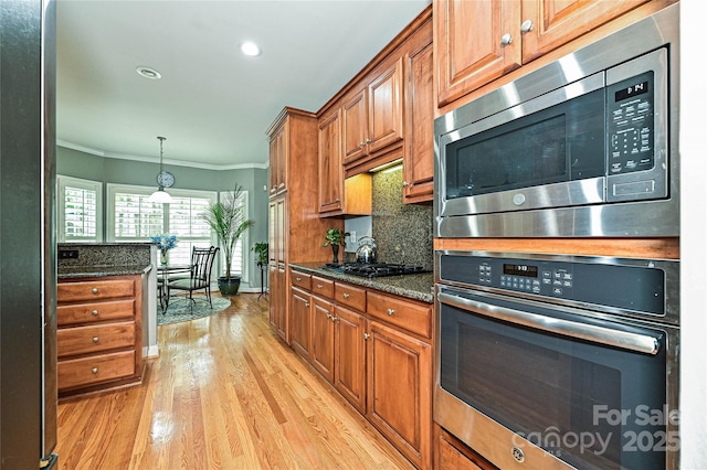 11232 Tradition View Dr, Charlotte, NC 28269 - kitchen featuring appliances with stainless steel finishes, crown molding, brown cabinetry, light wood-type flooring, and tasteful backsplash
