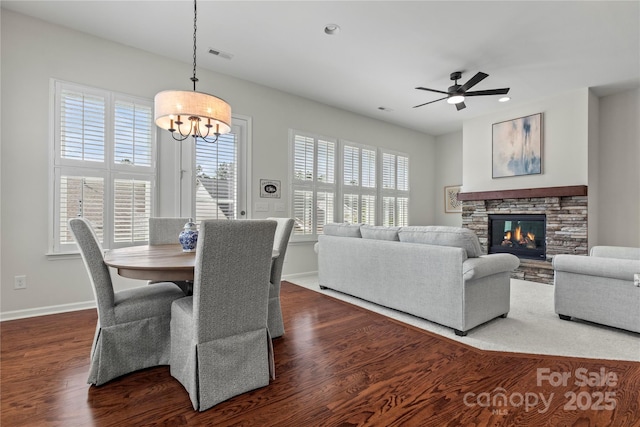 dining room featuring dark wood-type flooring, baseboards, ceiling fan with notable chandelier, and a wealth of natural light